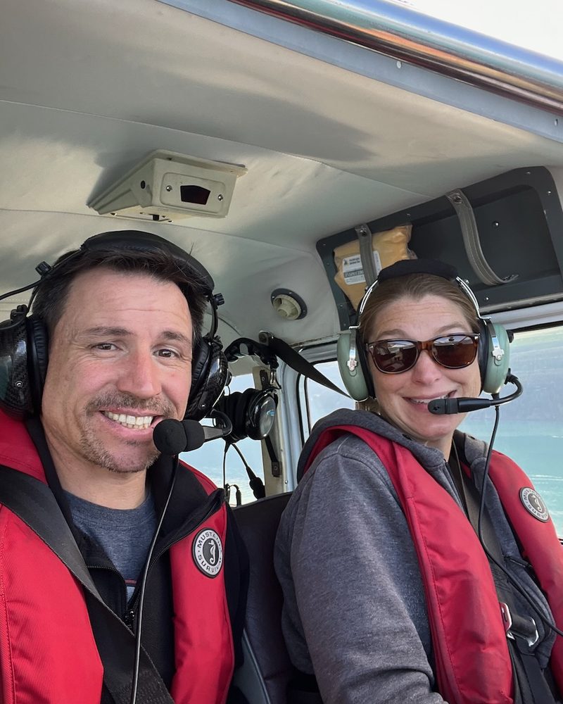 The Quinn Aviation team in the cockpit, wearing headsets and life vests.